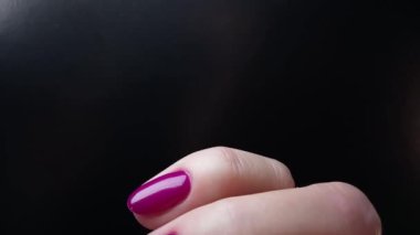 Manikürlü mor tırnaklı kadın eli. Kadın siyah arka planda parmaklarını ve manikürlü tırnaklarını gösteriyor. Yakın çekim görüntüsü. Güzel cazibe doymuş jöle oje rengi 