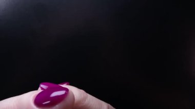 Manikür ve manikür. Kadın parmakları birbirine karışır. Parlak mor renkli oje, siyah arka planda yumuşak beyaz ten. Güzellik, moda, el derisi konsepti