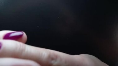 Tırnak sanatı ve manikür. Mor tırnaklı kadın elleri. Reklam jeli ojesi için yaratıcı bir video. Siyah arkaplandaki kadın parmaklarına yakın çekim yavaş çekim