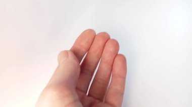 Beyaz haplar şişeden bir kadının avucuna düşer. Kadın elinin yakın çekim görüntüsü