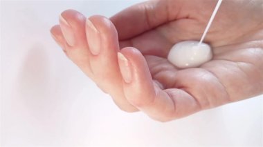 Vücut losyonu, el kremi, vücut sütü, şampuan veya duş jeli reklamı videosu. Kadın avucunun içine kozmetik bir ürün döküyor. Kadın eli ve parmaklarının çıplak tırnakları ve zarif manikürünün yakın çekimi.