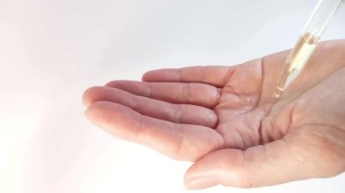 Kuru cilt bakımı kozmetiği ya da doğal masaj yağı reklamı. Bir kadın eline pipetle birkaç damla serum yağı ve hyaluronik asit sürer.