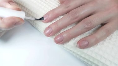 Jel cilası manikür, adım adım video eğitimi. Altıncı adım Asal uygulama. Kadın, en uygun yapışıklığı sağlamak için tırnaklara ultra-bağ astarı uyguluyor. Evde manikür, güzellik, kişisel bakım konsepti