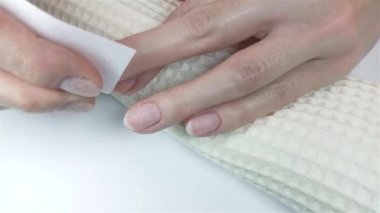 Jel cilası manikür, adım adım video eğitimi. Beşinci adım tırnak hazırlığı. Kadın nemden kurtulmak ve çivi yüzeyini dezenfekte etmek için ipliksiz peçete ve kurutucu kullanıyor.
