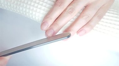 Jel cilası manikür, adım adım video eğitimi. Tırnaklar doluyor. Çivilerin şeklini dosyalama işlemi. Bir kadın üst katmanı lazer olan bir dosya kullanıyor. Çivi bakımı kavramı
