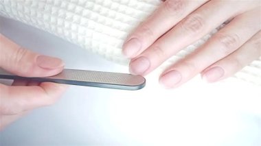 Jel cilası manikür, adım adım video eğitimi. Tırnaklar doluyor. Lazer tırnak törpüsü bir kadının tırnağını şekillendirir. Yakın çekim görüntüsü. Evde manikür ve tırnak bakımı konsepti