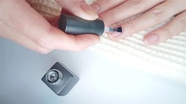 Jel cilası manikür, adım adım video eğitimi. 7. adım Nails astarı. Bir kadın yakın plan çekiminde tırnaklarına oje sürüyor.