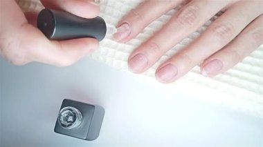 Jel cilası manikür, adım adım video eğitimi. 7. adım Nails astarı. Tırnaklarına astar boyası süren bir kadının yakın çekimi.