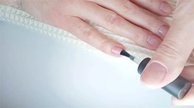 Jel cilası manikür kılavuzu adım adım. 7. adım Nails astarı. Bir kadın sağ elinin serçe parmağına şeffaf bir jel tabanlı ceket uygular. Evde manikür.