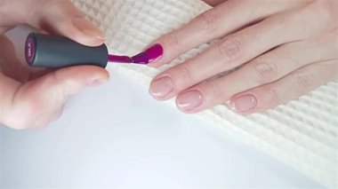 Jel cilası manikür, adım adım video eğitimi. 8. adım oje sürme. Bir kadın parlak mor jel cilasıyla tırnaklarını boyuyor. Kendin için ev yapımı manikür.