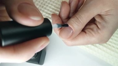 Jel cilası manikür, adım adım video rehberi. 7. adım Nails astarı. Bir kadın nazikçe tırnağa şeffaf bir jel tabanı sürer. Kendin için ev yapımı manikür.