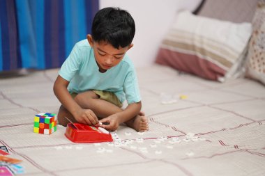 Yatağında Scrabble alfabesi olan neşeli çocuk. Çocuk projeleri için ideal. Öğrenmek için ilgi çekici kavram. Web siteleri, reklamlar ve eğitim için mükemmel.