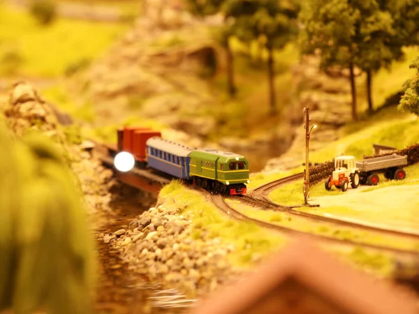 Diesel locomotive pulls wagons along the railroad in a picturesque place. layout of the landscape with the railway, cars, residential and industrial buildings. Monuments of architecture and sights