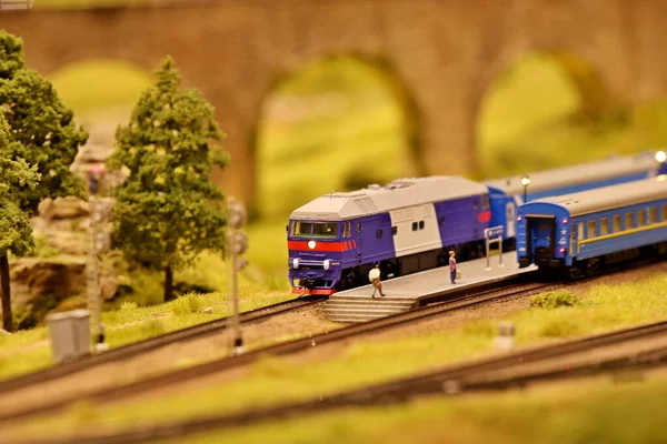 Diesel locomotive pulls wagons along the railroad in a picturesque place. layout of the landscape with the railway, cars, residential and industrial buildings. Monuments of architecture and sights