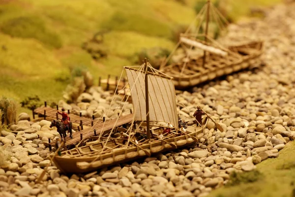 Ancient sailing ships near the river pier. Landscape layout with railroad, cars, residential and industrial buildings. Monuments of architecture and sights. Hobbies of building miniatures