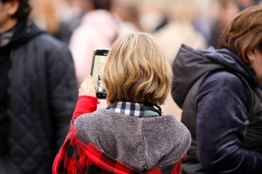 Güzellik, kalabalığın içinde cep telefonuyla kollarını açarak fotoğraf çekiyor. Konserde güzel elbiseli güzel bir kız cihazıyla video çekiyor. Seyahat belleği