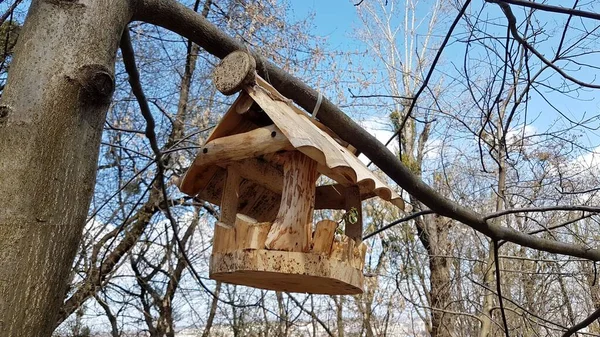 ログハウスの家のスタイルで木で作られた木製の鳥のフィーダー 公園やレクリエーションエリアの装飾的なデザイン 手作りの木製品 冬の困難な時期に都市の鳥に餌を与える — ストック写真