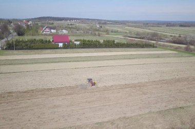 Bir çiftçi bir sembol ile kırmızı bir traktör tahıl köyü alan özel bir alanda sürülmüş topraklarda sows. Mekanizasyon bahar saha çalışması. Çiftçinin günlük yaşam. Toprak işleme. Tarım.