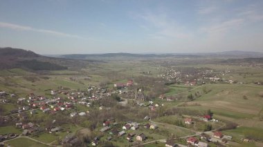 Cieklin, Poland - 4 9 2019: Panorama of a small European village with a Christian Catholic church in the center. Farms among green picturesque hills. Panorama of the Carpathian region with a drone.