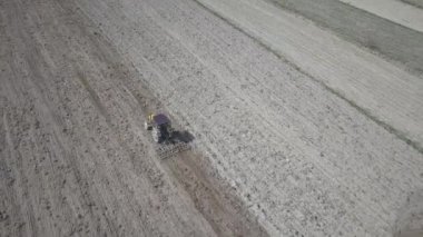 Bir çiftçi bir sembol ile kırmızı bir traktör tahıl köyü alan özel bir alanda sürülmüş topraklarda sows. Mekanizasyon bahar saha çalışması. Çiftçinin günlük yaşam. Toprak işleme. Tarım.