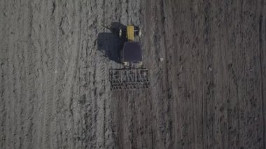 Bir çiftçi bir sembol ile kırmızı bir traktör tahıl köyü alan özel bir alanda sürülmüş topraklarda sows. Mekanizasyon bahar saha çalışması. Çiftçinin günlük yaşam. Toprak işleme. Tarım.