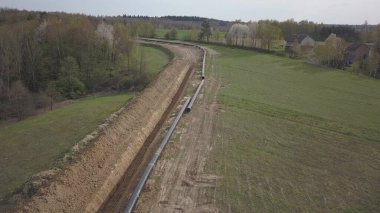 Yeşil tepelerin arasına gaz boru hattı döşenmesi. Kazılan sipere dalmak için hazırlanmış büyük yüksek basınçlı çelik borular. Stratejik endüstride arazi işleri. Enerji ve doğal kaynaklar