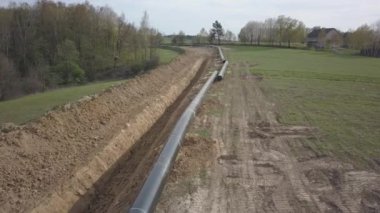 Yeşil tepelerin arasına gaz boru hattı döşenmesi. Kazılan sipere dalmak için hazırlanmış büyük yüksek basınçlı çelik borular. Stratejik endüstride arazi işleri. Enerji ve doğal kaynaklar