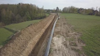 Yeşil tepelerin arasına gaz boru hattı döşenmesi. Kazılan sipere dalmak için hazırlanmış büyük yüksek basınçlı çelik borular. Stratejik endüstride arazi işleri. Enerji ve doğal kaynaklar