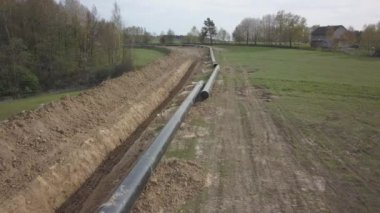 Yeşil tepelerin arasına gaz boru hattı döşenmesi. Kazılan sipere dalmak için hazırlanmış büyük yüksek basınçlı çelik borular. Stratejik endüstride arazi işleri. Enerji ve doğal kaynaklar