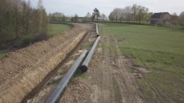 Yeşil tepelerin arasına gaz boru hattı döşenmesi. Kazılan sipere dalmak için hazırlanmış büyük yüksek basınçlı çelik borular. Stratejik endüstride arazi işleri. Enerji ve doğal kaynaklar