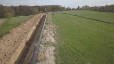 Yeşil tepelerin arasına gaz boru hattı döşenmesi. Kazılan sipere dalmak için hazırlanmış büyük yüksek basınçlı çelik borular. Stratejik endüstride arazi işleri. Enerji ve doğal kaynaklar
