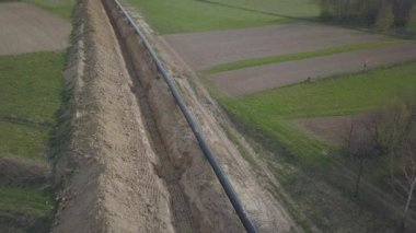 Yeşil tepelerin arasına gaz boru hattı döşenmesi. Kazılan sipere dalmak için hazırlanmış büyük yüksek basınçlı çelik borular. Stratejik endüstride arazi işleri. Enerji ve doğal kaynaklar