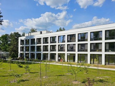 Design of the facade of a modern hotel-type building. A rectangular white architectural structure among a green forest. clipart