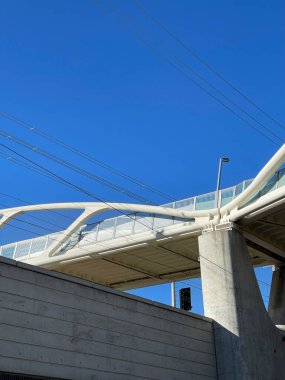 Güneşli bir günde mavi gökyüzünün altında modern beyaz bir köprünün alçak açılı görüntüsü.