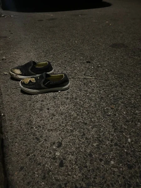 被撕破的小孩鞋子扔在水泥路上 — 图库照片