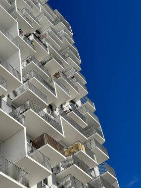 Mavi gökyüzünün altında minimalist geometrik dış görünüşlü beyaz bir apartmanın kırpılmış görüntüsü.