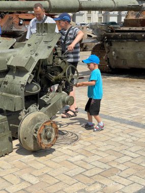 Ukrayna 'da savaş. Ukrayna 'nın başkenti Kyiv' de 17 Haziran 2022 'de imha edilmiş ağır silah parçalarıyla oynayan küçük çocuk.