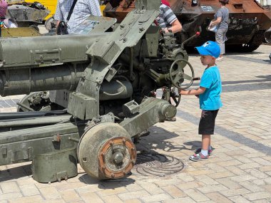 Ukrayna 'da savaş. Ukrayna 'nın başkenti Kyiv' de 17 Haziran 2022 'de imha edilmiş ağır silah parçalarıyla oynayan küçük çocuk.