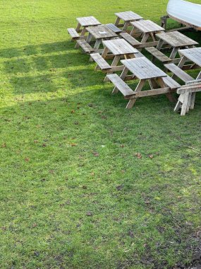 Wooden picnic tables on green grass, copy space