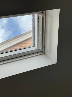Tavandaki küçük bir pencerenin kırpılmış görüntüsü, mavi gökyüzü