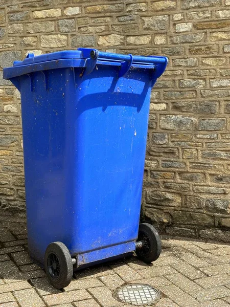 レンガの壁の前に青いリサイクルゴミ箱の垂直ショット — ストック写真