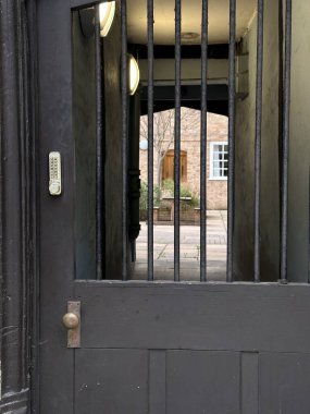 Metal kapının içinden görünen rahat iç avlu.