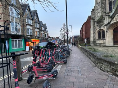 Birçok elektrikli scooter ve bisiklet şehir caddesinde üst üste dizilmiştir.