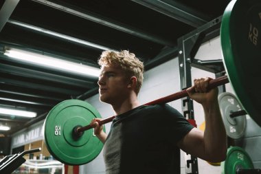Yakışıklı bir sporcunun Crossfit spor salonunda halter egzersizi yaparken düşük açılı çekimi.