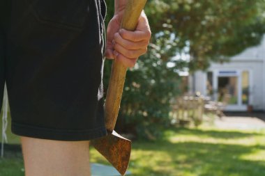 Elinde baltayla evin önünde duran bir adamın dikiz görüntüsü.