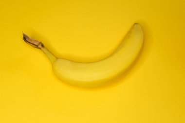 Sarı arkaplanda sarı bir muzun üst görünümü