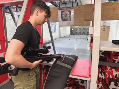 Atış poligonunda havalı tüfekli genç bir adam.