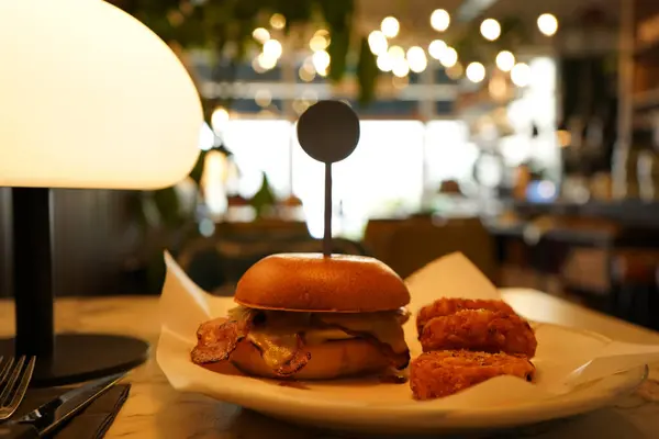 stock image Delicious burger and hashbrowns side on a plate at a cozy restaurant