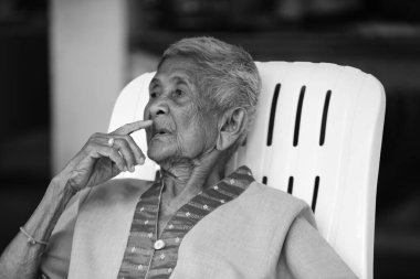 Taylandlı yaşlı adamın portresi sandalyede oturuyor. 