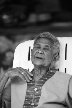 Taylandlı yaşlı adamın portresi sandalyede oturuyor. 